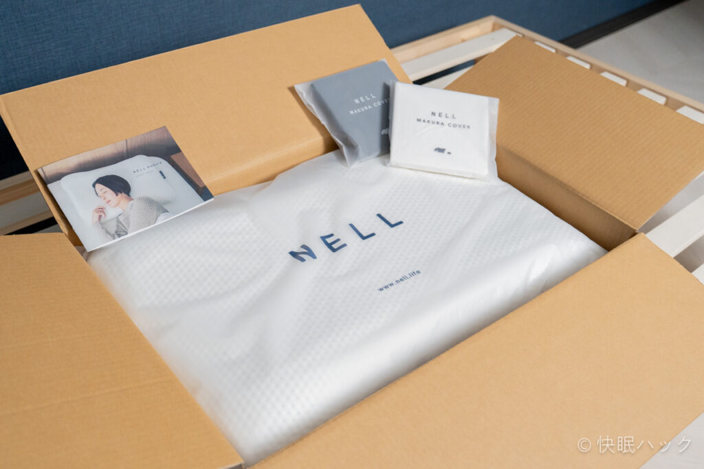 ネル枕（NELL まくら）の外箱を開けると、枕本体の他に付属のNELLまくらカバーと取扱説明書が入っている。